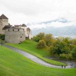 Camino pavimentado que conduce al palacio real del castillo de Vaduz - Cosas que hacer en Liechtenstein con montañas al fondo