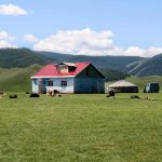 Una casa azul con un techo rojo y un blanco Ger se sienta aislado en el valle de Orkhon de Mongolia